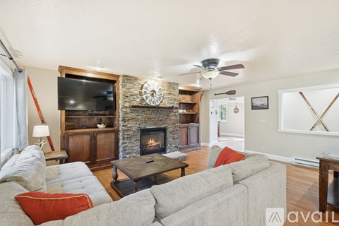 A living room with a grey couch and a stone fireplace.