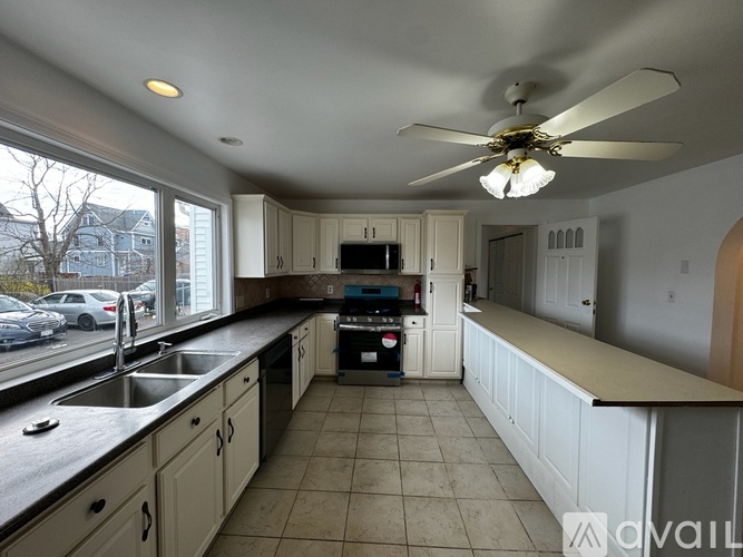 A kitchen with a fan and a black counter top.