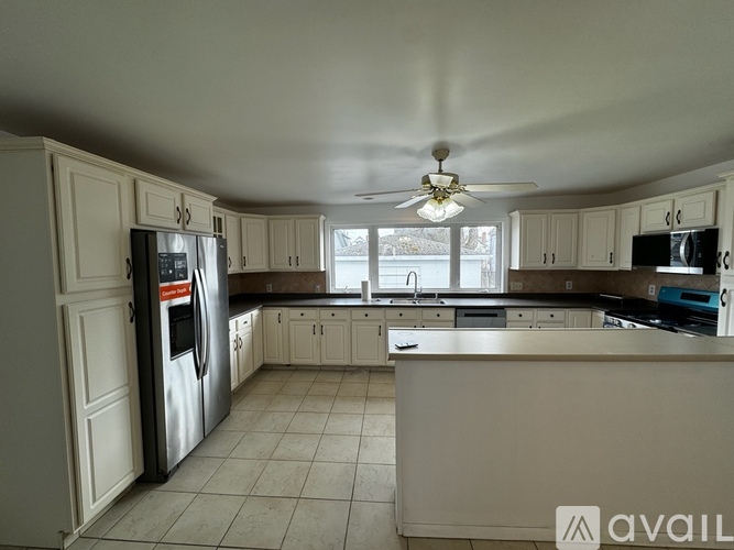 A kitchen with white cabinets and a refrigerator.