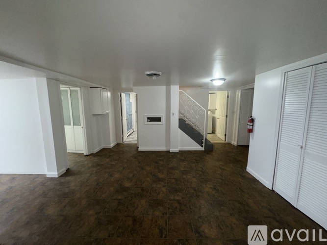 A spacious room with wooden flooring and white walls.