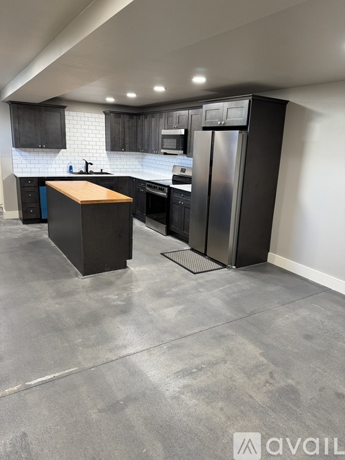 A modern kitchen with a wooden island and stainless steel appliances.