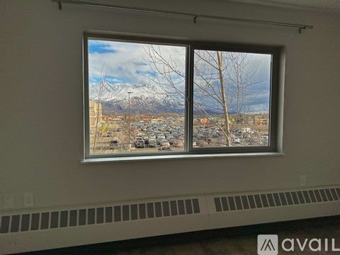 A window with a view of a snowy mountain and a parking lot.