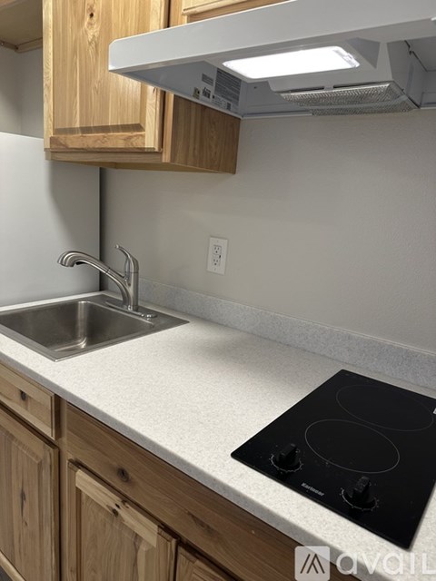 A kitchen with a black stove top and wooden cabinets.