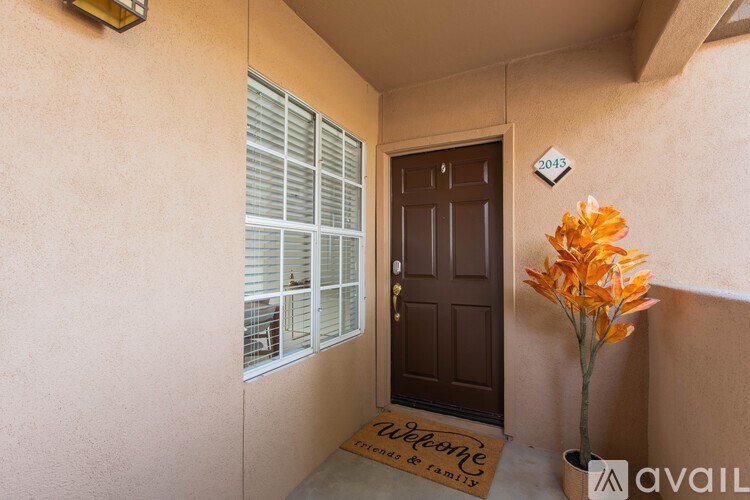 A brown door with a welcome mat and a plant in front of it.