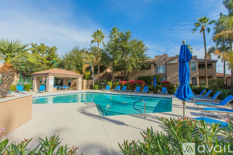 A pool surrounded by blue lounge chairs and umbrellas.
