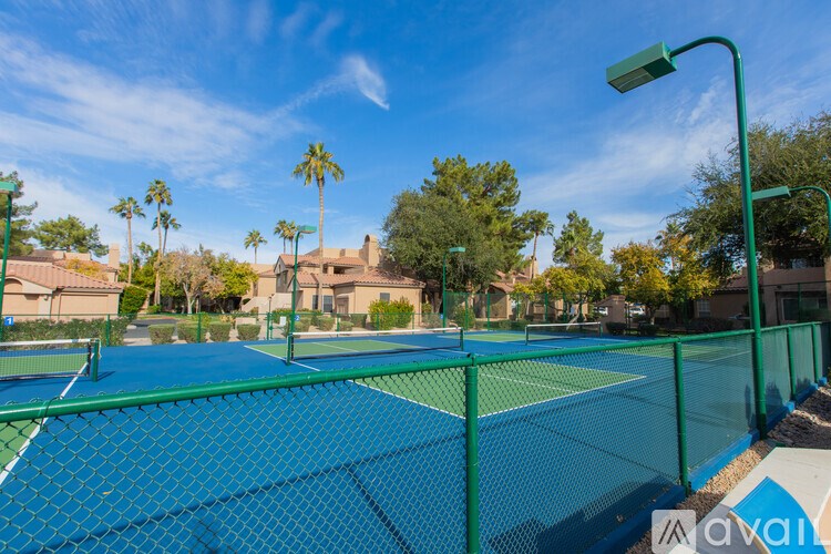Tennis court surrounded by a green fence.
