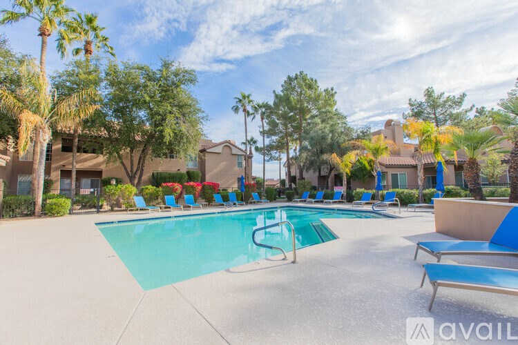 A pool surrounded by palm trees and blue lounge chairs.