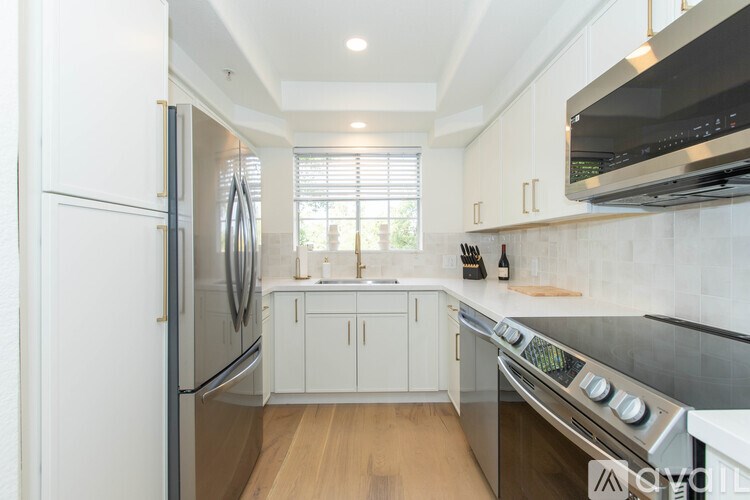 A modern kitchen with white cabinets and stainless steel appliances.