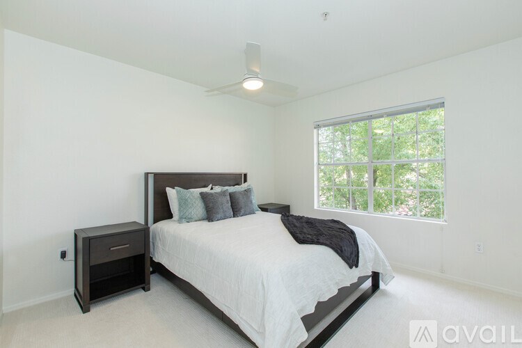 A bedroom with a large bed and a window overlooking trees.
