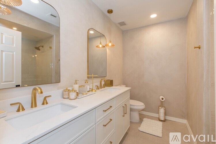 A bathroom with a white sink and gold fixtures.