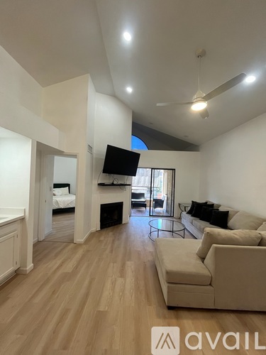 A living room with a television, couch, and a fireplace.