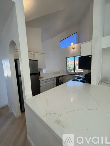 A kitchen with a marble countertop and a refrigerator.