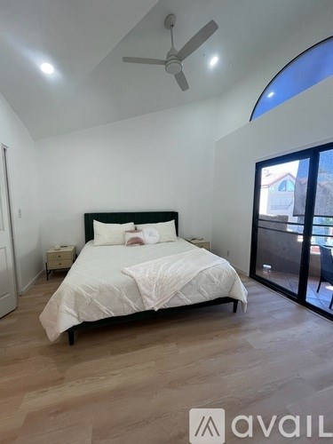 A bedroom with a large bed and a ceiling fan.