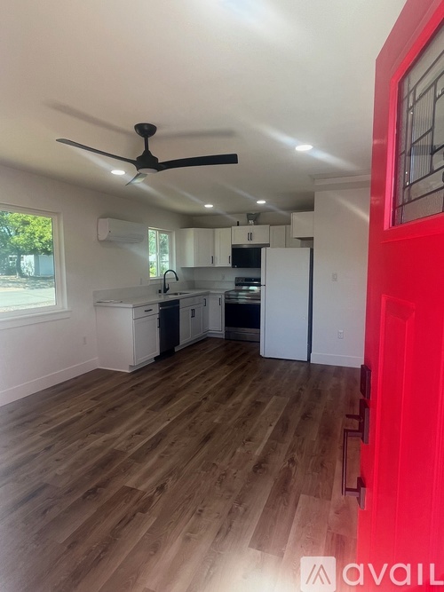 A kitchen with a fan and wooden floors.