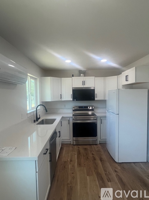A kitchen with white cabinets and a wooden floor.