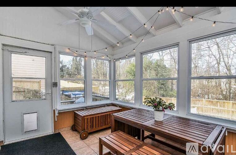 A sunroom with a ceiling fan and wooden furniture.