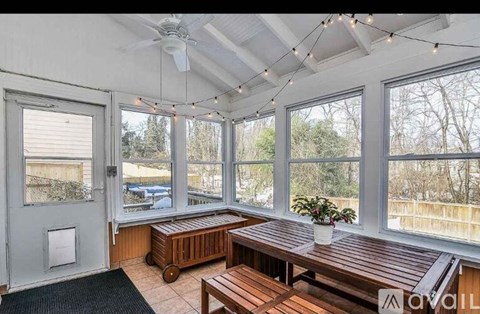A sunroom with a ceiling fan and wooden furniture.