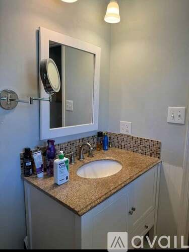 A bathroom with a sink, mirror, and a few toiletries on the counter.