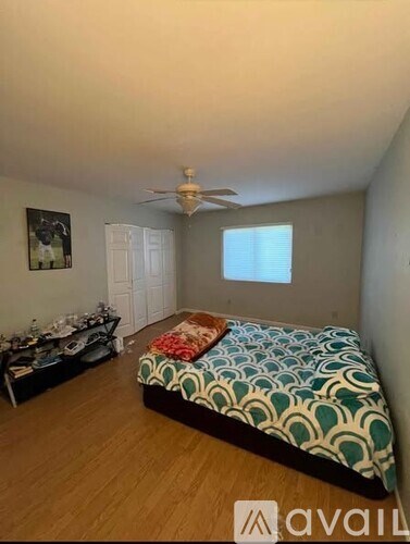 A bedroom with a bed, dresser, and a ceiling fan.