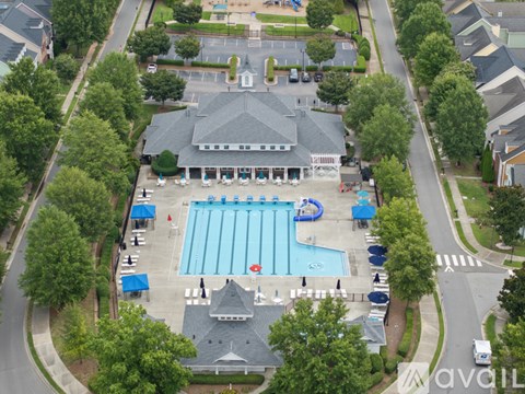 An aerial view of a swimming pool surrounded by trees and a building.