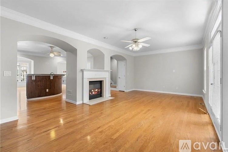 A spacious living room with wood flooring and a fireplace.