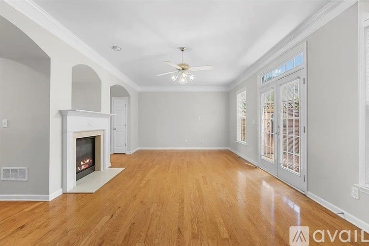 A spacious room with a fireplace and wooden flooring.