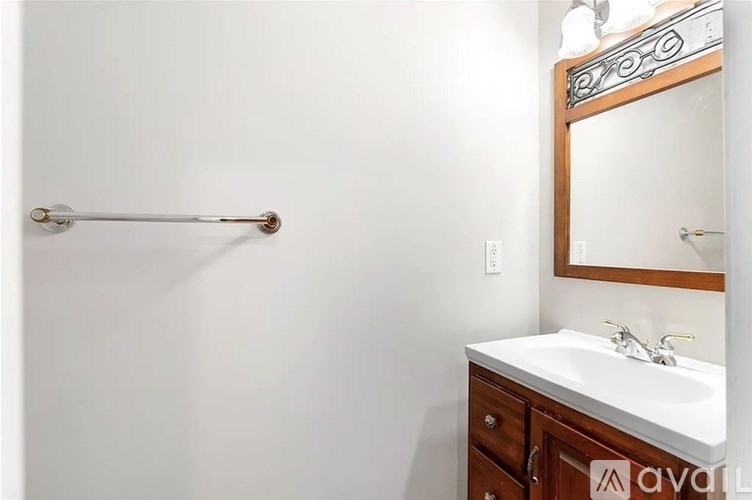 A bathroom with a white sink and a mirror with a wooden frame.