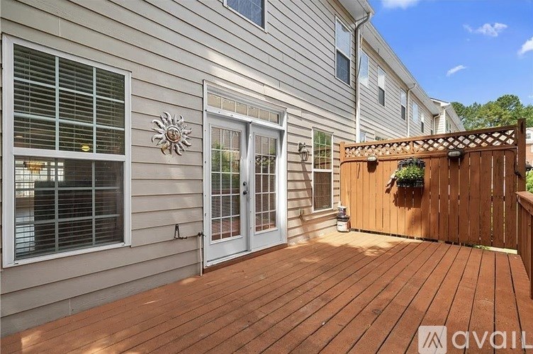 A wooden deck is attached to a house with a sliding glass door.