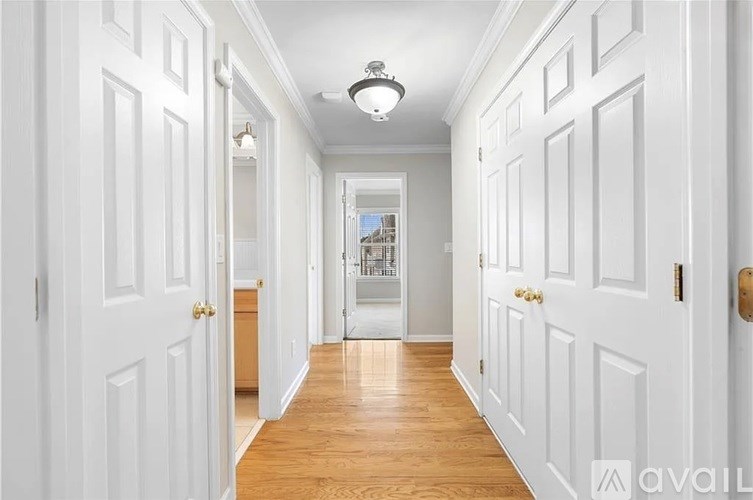 A hallway with white doors and wooden floors.