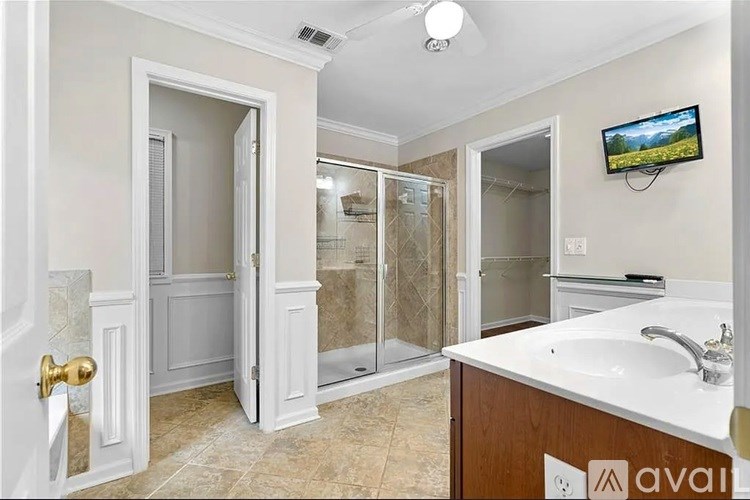 A bathroom with a sink, mirror, and shower.
