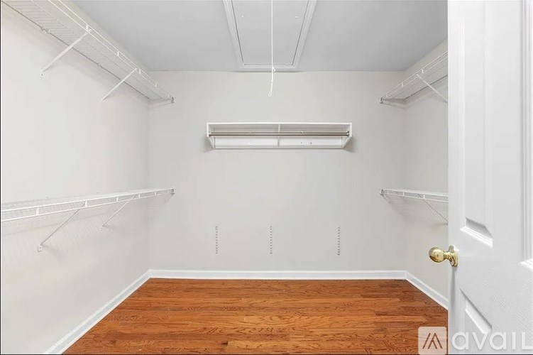 A room with white walls, wooden floor, and a white door.