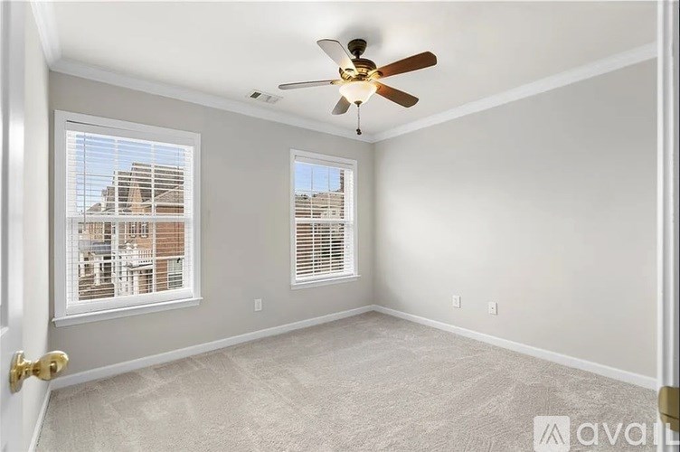 A room with a ceiling fan and two windows.