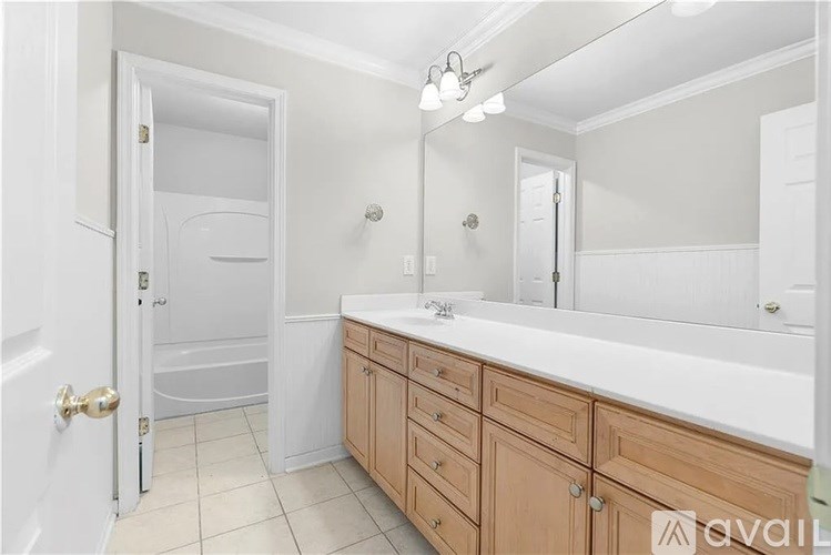 A bathroom with a white countertop and wooden cabinets.