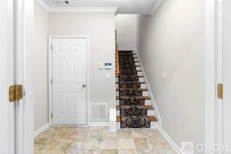 A hallway with a white door and a staircase with a black and white patterned runner.