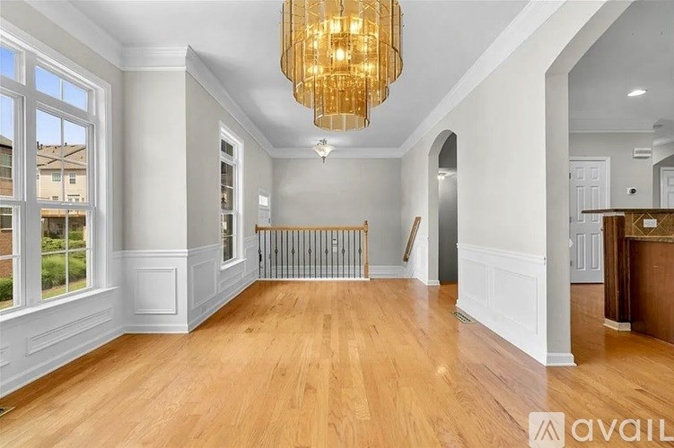 A large, empty room with wooden floors and a chandelier hanging from the ceiling.