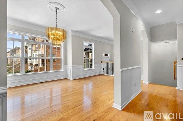 A large, empty room with wooden floors and a chandelier.