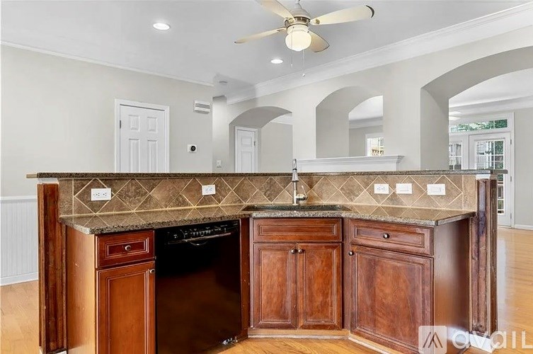 A kitchen with a dark counter top and wooden cabinets.