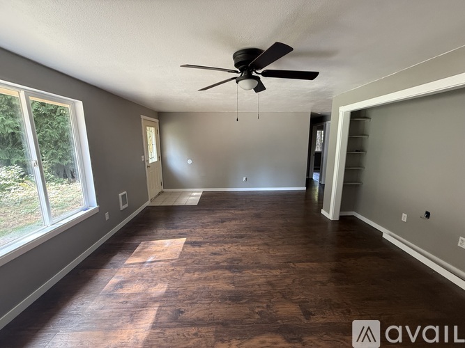 A spacious room with a ceiling fan and hardwood flooring.