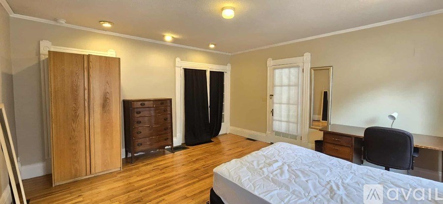 A bedroom with a large bed, a desk, and a wardrobe.