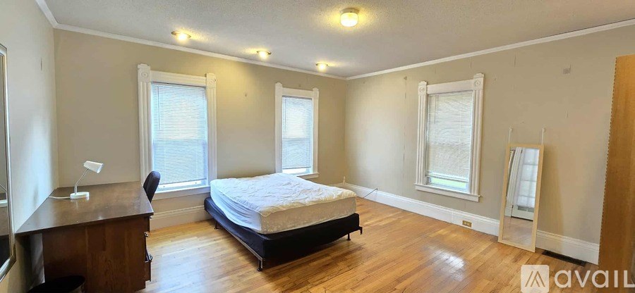 A bedroom with a bed, desk, and window.