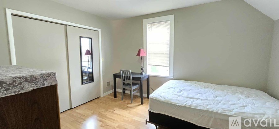 A bedroom with a bed, desk, and chair.