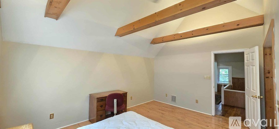 A bedroom with a bed, dresser, and a window.