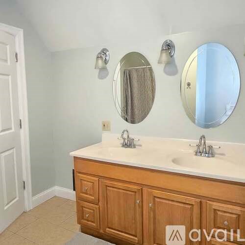 A bathroom with a vanity and two round mirrors.