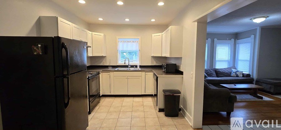 A bedroom with a bed, dresser, and window with black curtains.