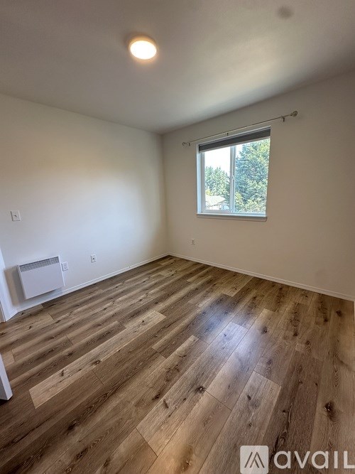 A room with wooden flooring and a window.