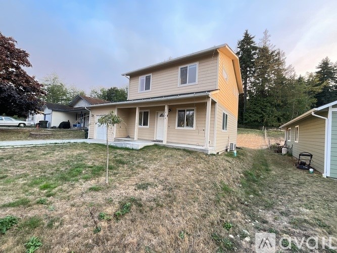 A house with a brown roof and a white garage door is surrounded by a grassy area.