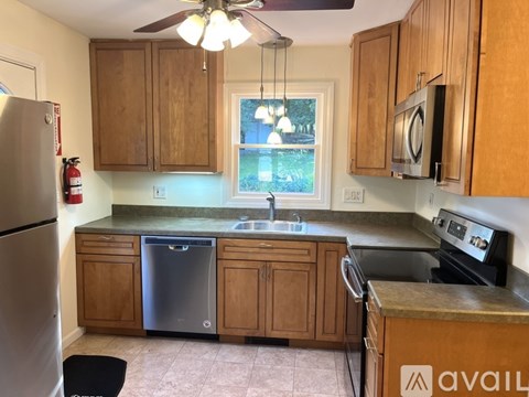A kitchen with wooden cabinets and a stainless steel dishwasher.