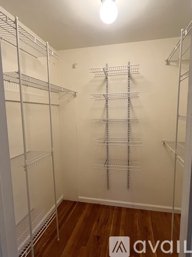 A walk-in closet with shelving and a wooden floor.