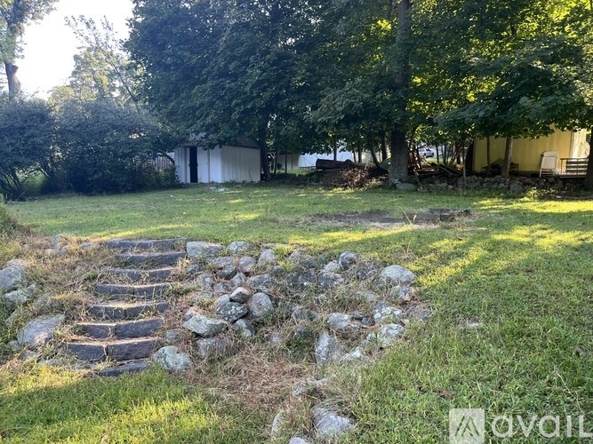 A stone staircase leads up to a grassy area with a shed in the background.