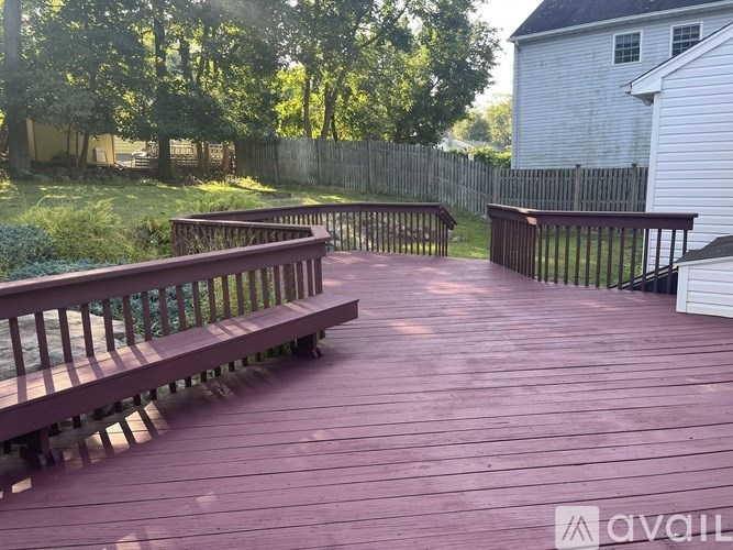 A wooden deck with benches and a fence in the background.